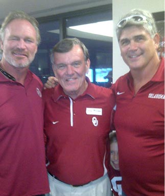 Three men in red shirts are posing for a picture.